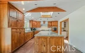a view of a kitchen with kitchen island granite countertop wooden floor and stainless steel appliances