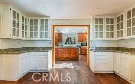 a kitchen with granite countertop white cabinets and wooden floor