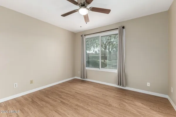 a view of an empty room with wooden floor and a window