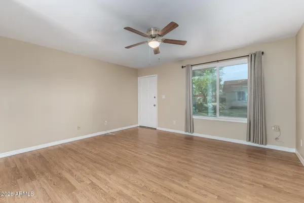 a view of an empty room with wooden floor and a window