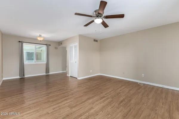 an empty room with wooden floor fan and windows