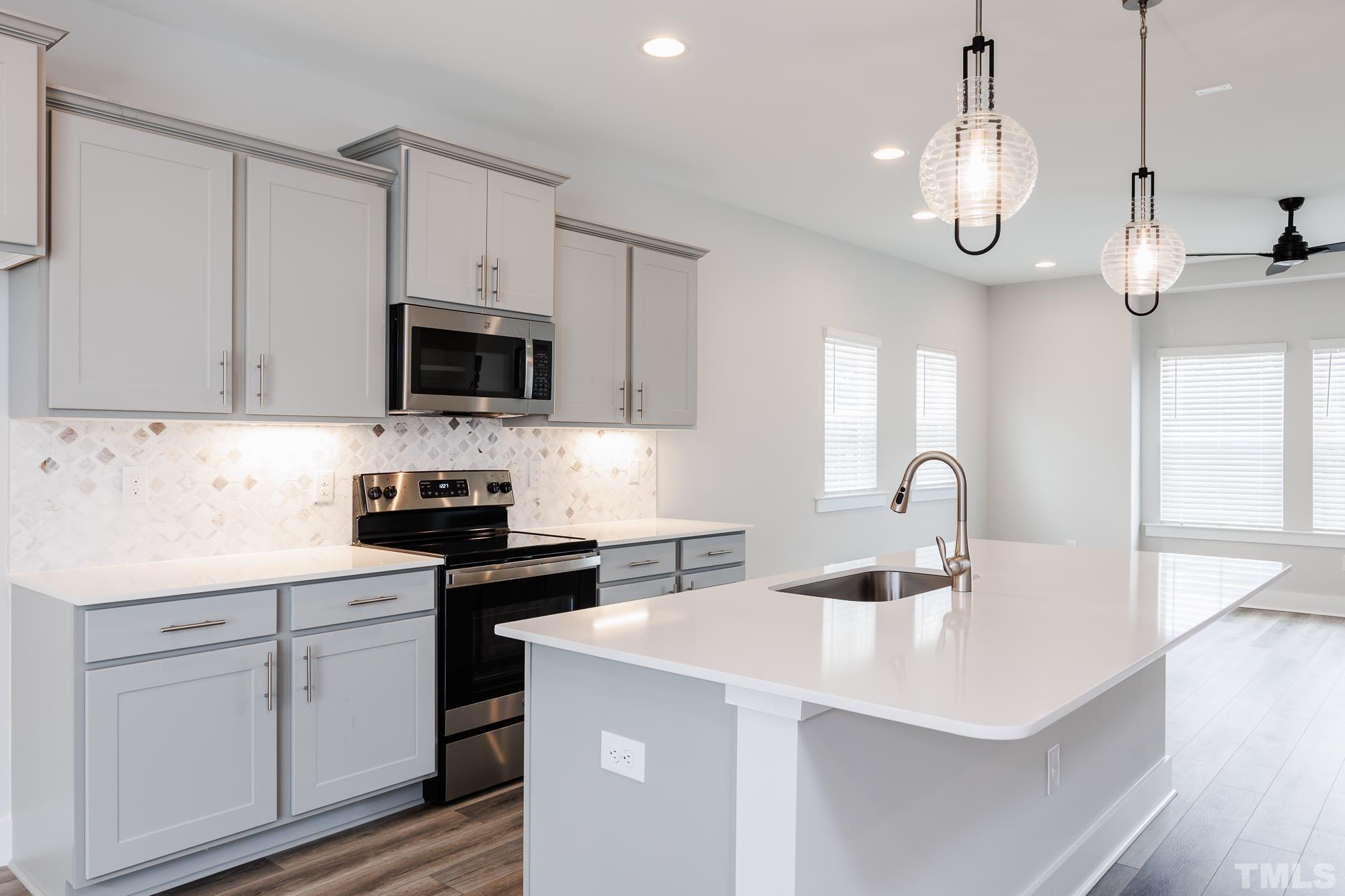 8226 Ebenezer Church Road Raleigh, NC 27613 - Photo 2 of 16 a kitchen with kitchen island granite countertop a sink a stove and cabinets