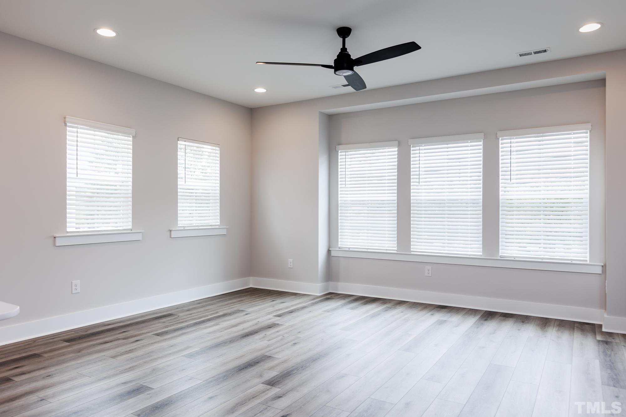 8226 Ebenezer Church Road Raleigh, NC 27613 - Photo 7 of 16 a view of empty room with wooden floor and fan