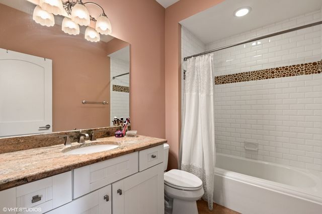 a bathroom with a granite countertop sink a toilet and shower
