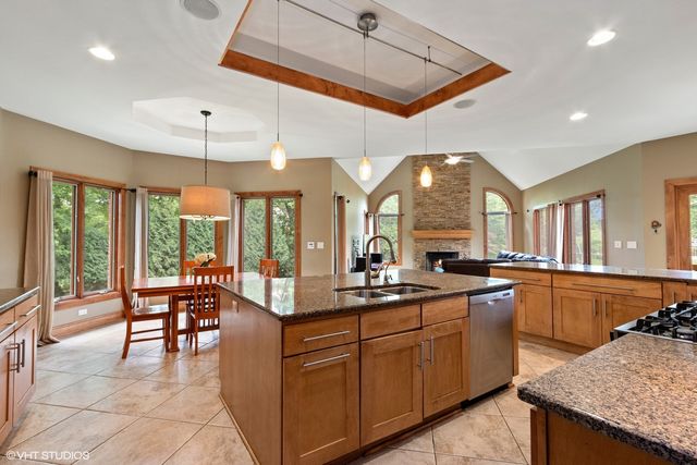 a large kitchen with kitchen island granite countertop a large window cabinets and stainless steel appliances