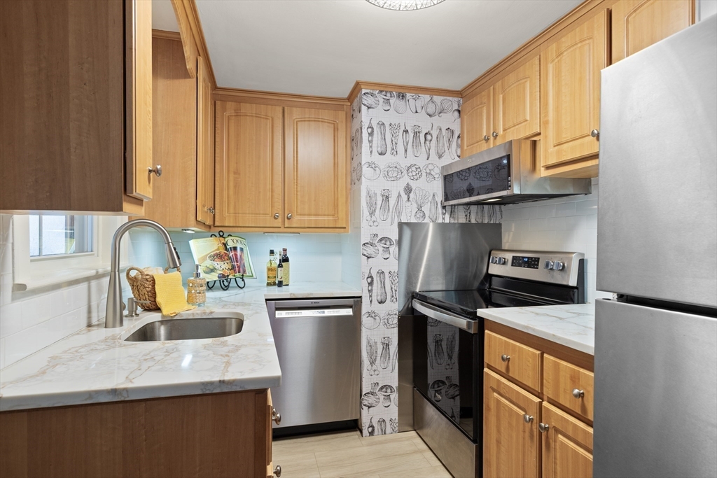50 Forest Street Reading, MA 01867 - Photo 16 of 42 a kitchen with stainless steel appliances granite countertop a sink stove and refrigerator