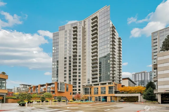 a front view of a building with lot of cars and trees