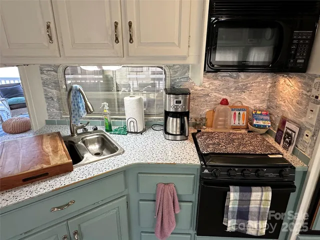 a kitchen with granite countertop a stove a microwave a sink and cabinets