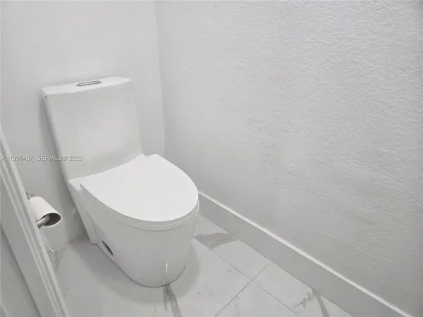 a white toilet sitting next to a white wall