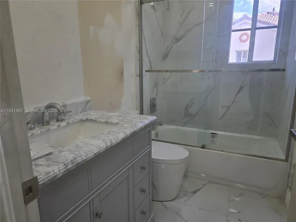 a bathroom with a granite countertop sink toilet and shower