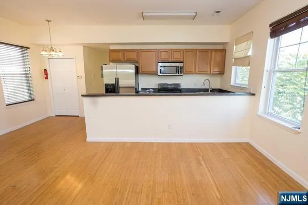 a large kitchen with stainless steel appliances a large counter top a wooden floor a stove and a window