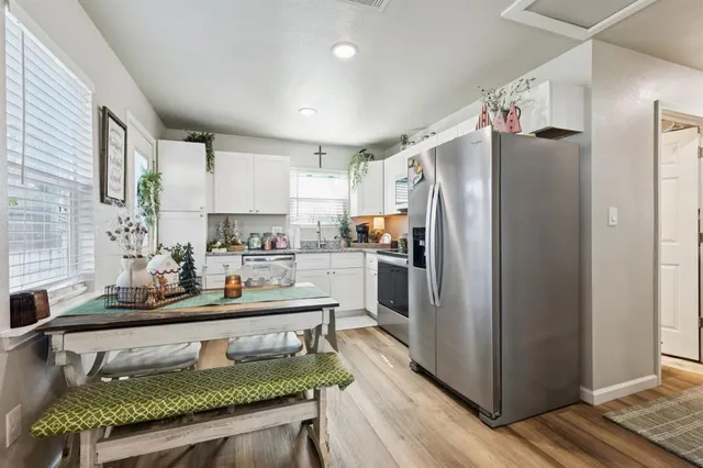 a kitchen with stainless steel appliances a stove a sink dishwasher a refrigerator with a dining table and chairs