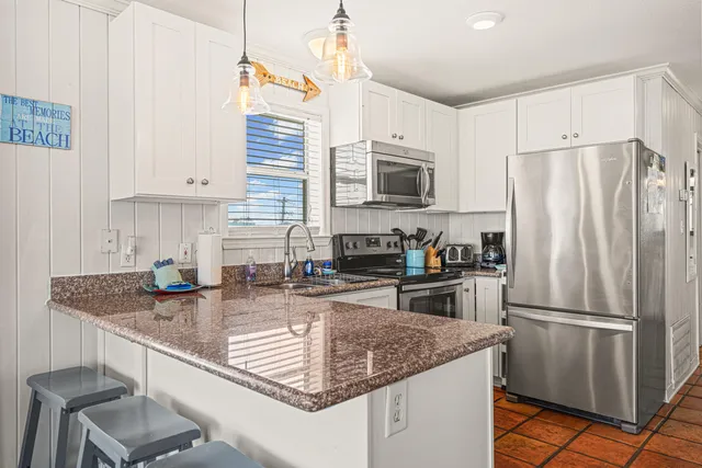 a kitchen with stainless steel appliances granite countertop a sink a refrigerator and a granite counter tops