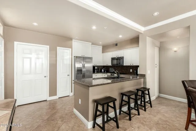 a kitchen with refrigerator and chairs