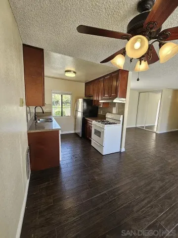 a living room with stainless steel appliances kitchen island granite countertop a stove and a wooden floors