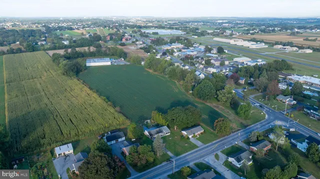 an aerial view of a residential houses with outdoor space and trees