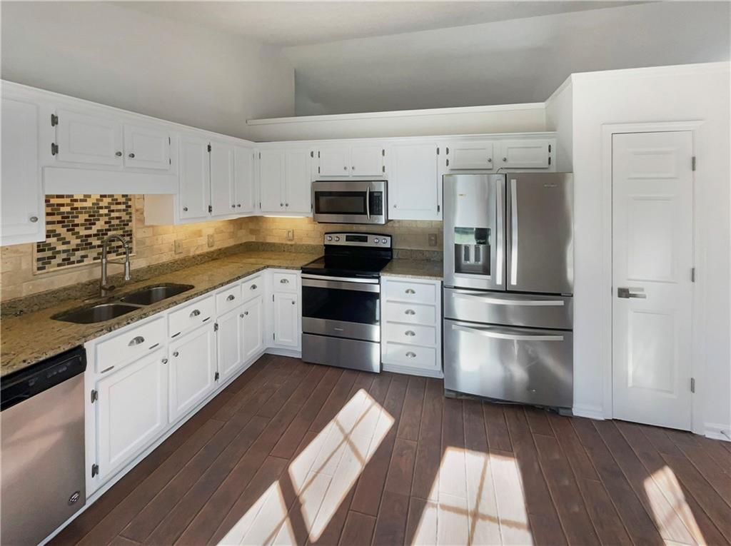 180 Honeysuckle Drive Southeast Calhoun, GA 30701 - Photo 5 of 21 a kitchen with granite countertop white cabinets and stainless steel appliances