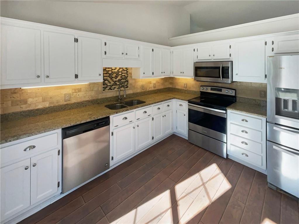 180 Honeysuckle Drive Southeast Calhoun, GA 30701 - Photo 6 of 21 a kitchen with granite countertop white cabinets and stainless steel appliances
