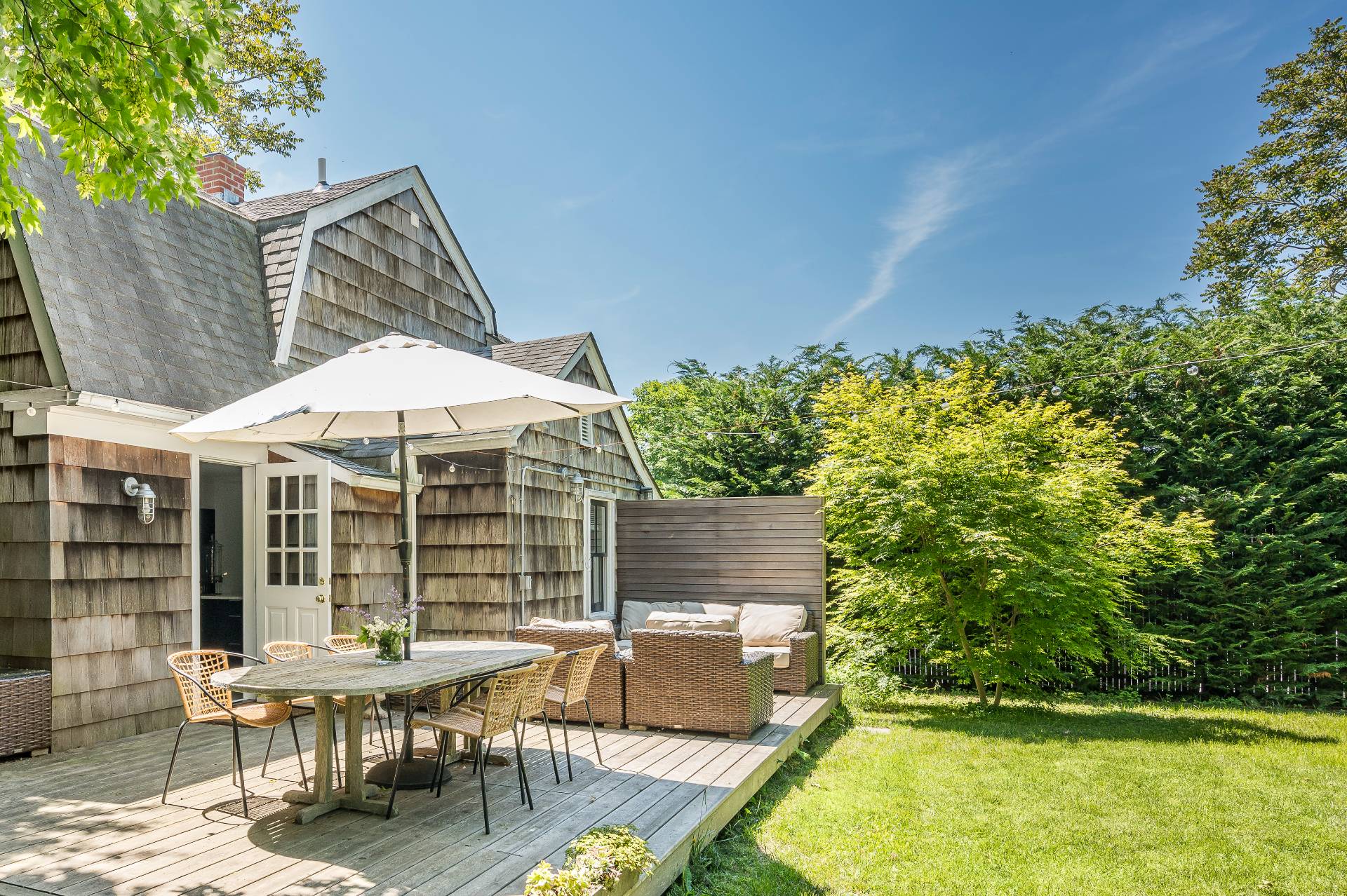 8 Collins Avenue East Hampton, NY 11937 - Photo 16 of 33 a view of a patio with table and chairs potted plants with wooden floor and fence