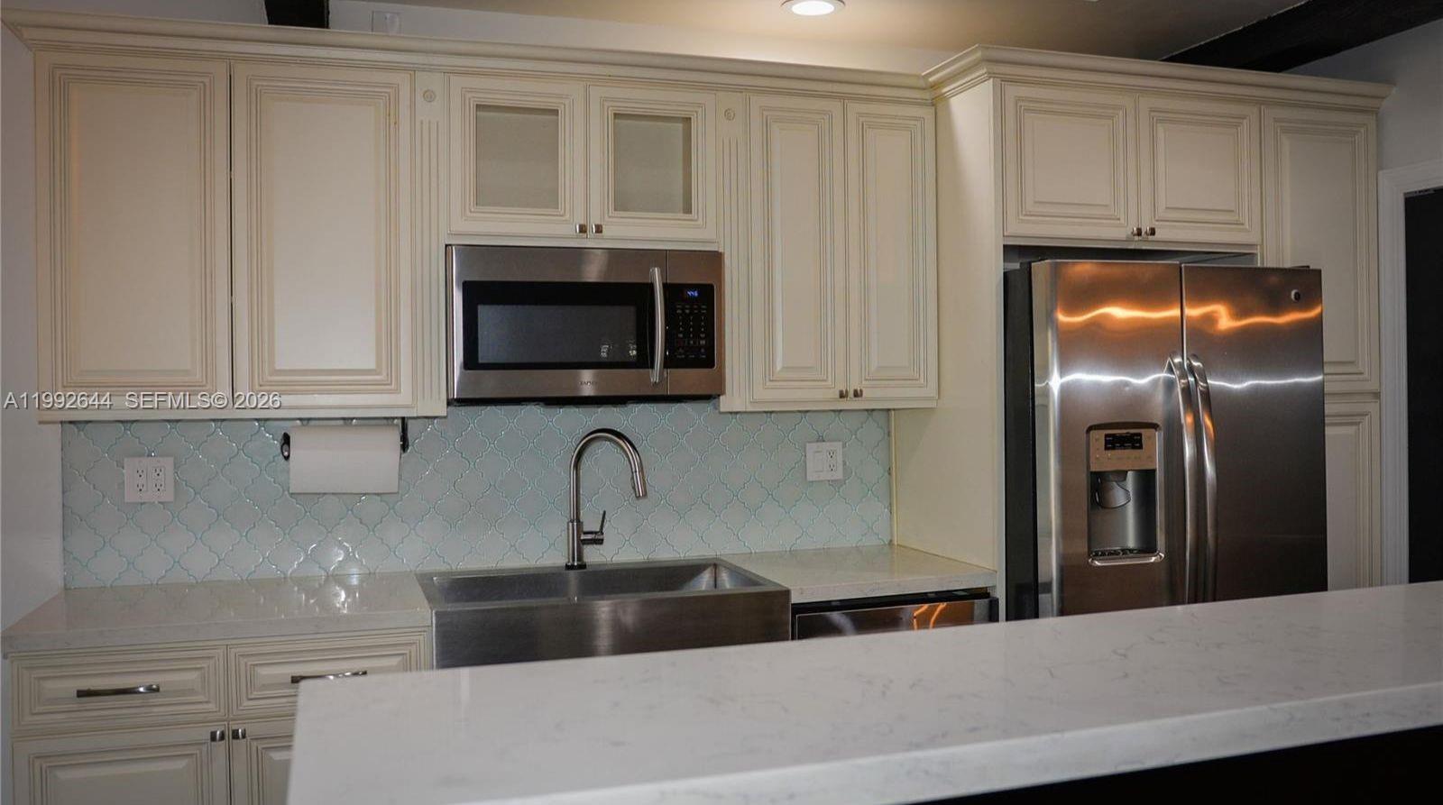 7849 Southwest 103rd Place Miami, FL 33173 - Photo 10 of 64 a kitchen with stainless steel appliances granite countertop a sink a microwave a refrigerator and white cabinets