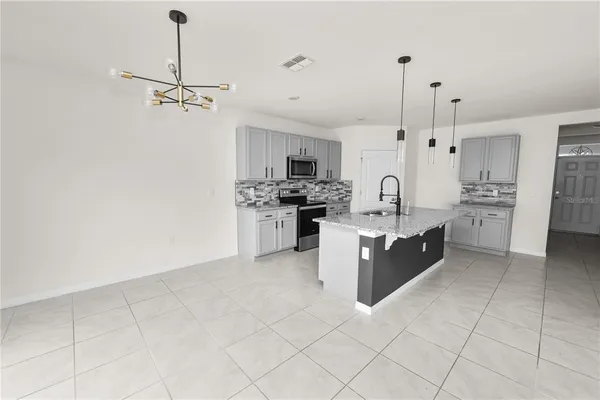 an empty room with chandelier fan and windows