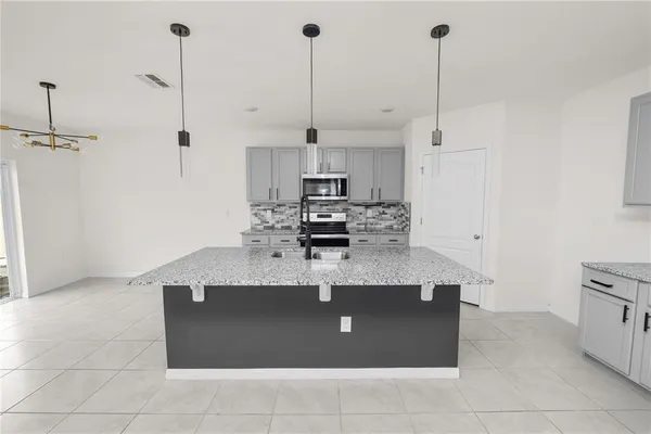 a kitchen with stainless steel appliances granite countertop a stove a microwave and a sink