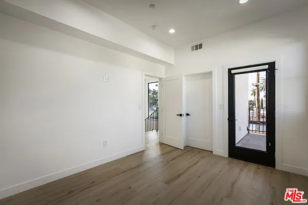 a view of an empty room with wooden floor and closet