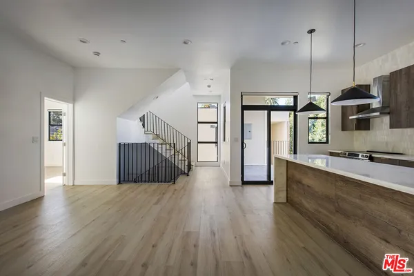 a kitchen with stainless steel appliances granite countertop a sink a microwave oven a refrigerator and wooden floors