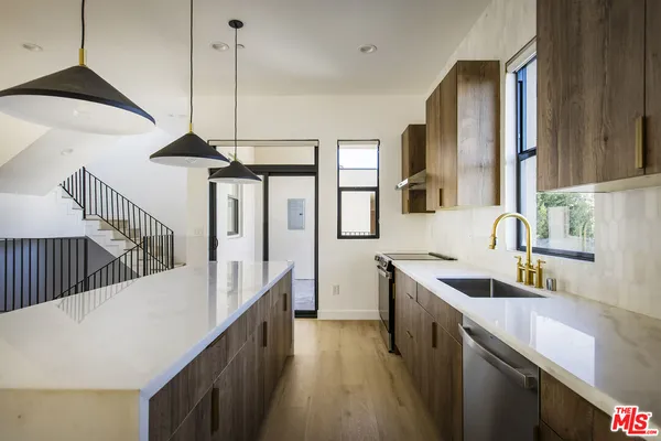 a kitchen with stainless steel appliances granite countertop a sink a stove and a wooden floors