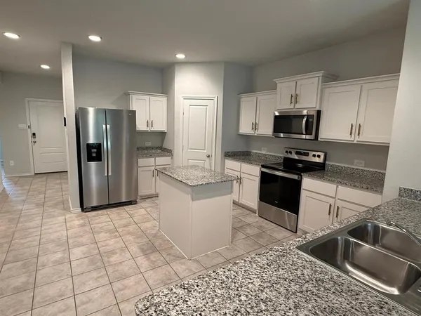 a kitchen with stainless steel appliances granite countertop a refrigerator a sink a stove a microwave and cabinets