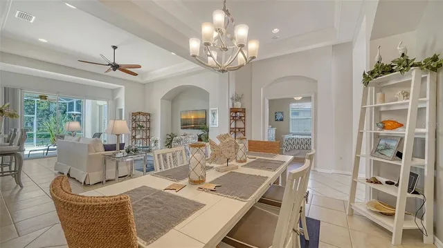 a dining room with wooden floor a chandelier a glass table and chairs