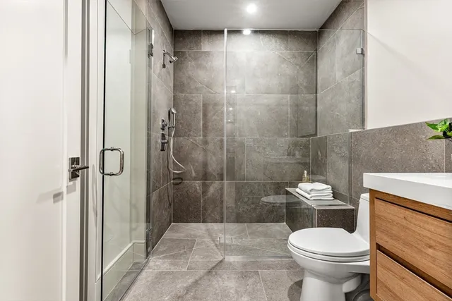 a white toilet sitting next to a bathroom sink and a shower