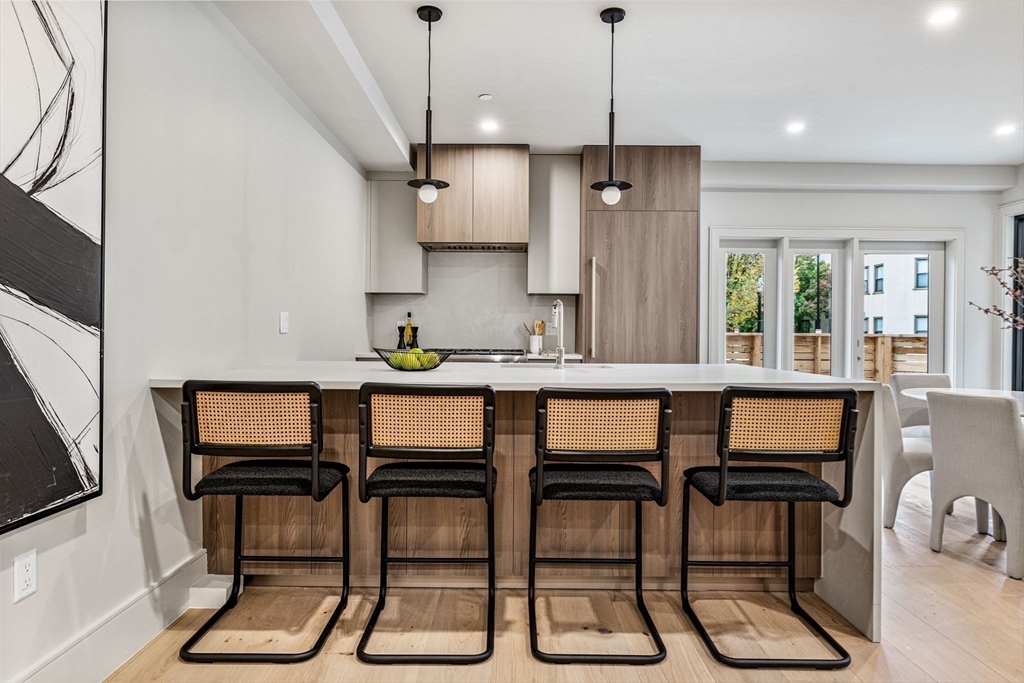 300 Franklin Street, Unit 1 Cambridge, MA 02139 - Photo 4 of 38 a kitchen with granite countertop a dining table chairs and white cabinets