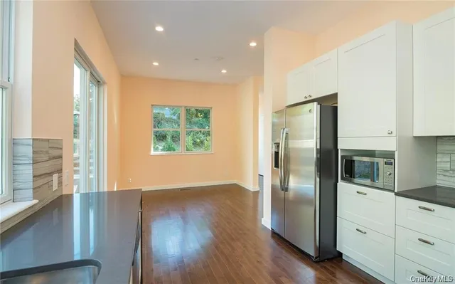 a large kitchen with stainless steel appliances granite countertop a refrigerator a sink dishwasher a stove and white countertops with wooden floor