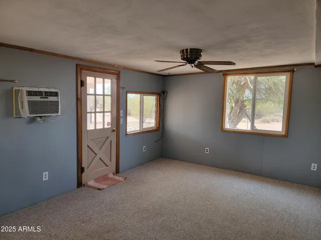 an empty room with windows and ceiling fan