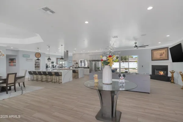 a dining room with kitchen island stainless steel appliances furniture a fireplace and a open kitchen view