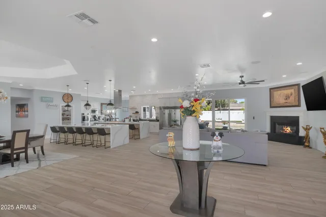 a dining room with kitchen island stainless steel appliances furniture a fireplace and a open kitchen view