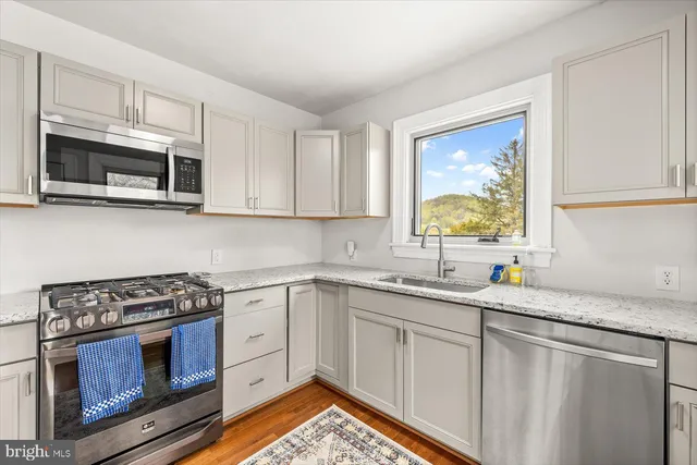 a kitchen with stainless steel appliances granite countertop a stove a sink and a microwave