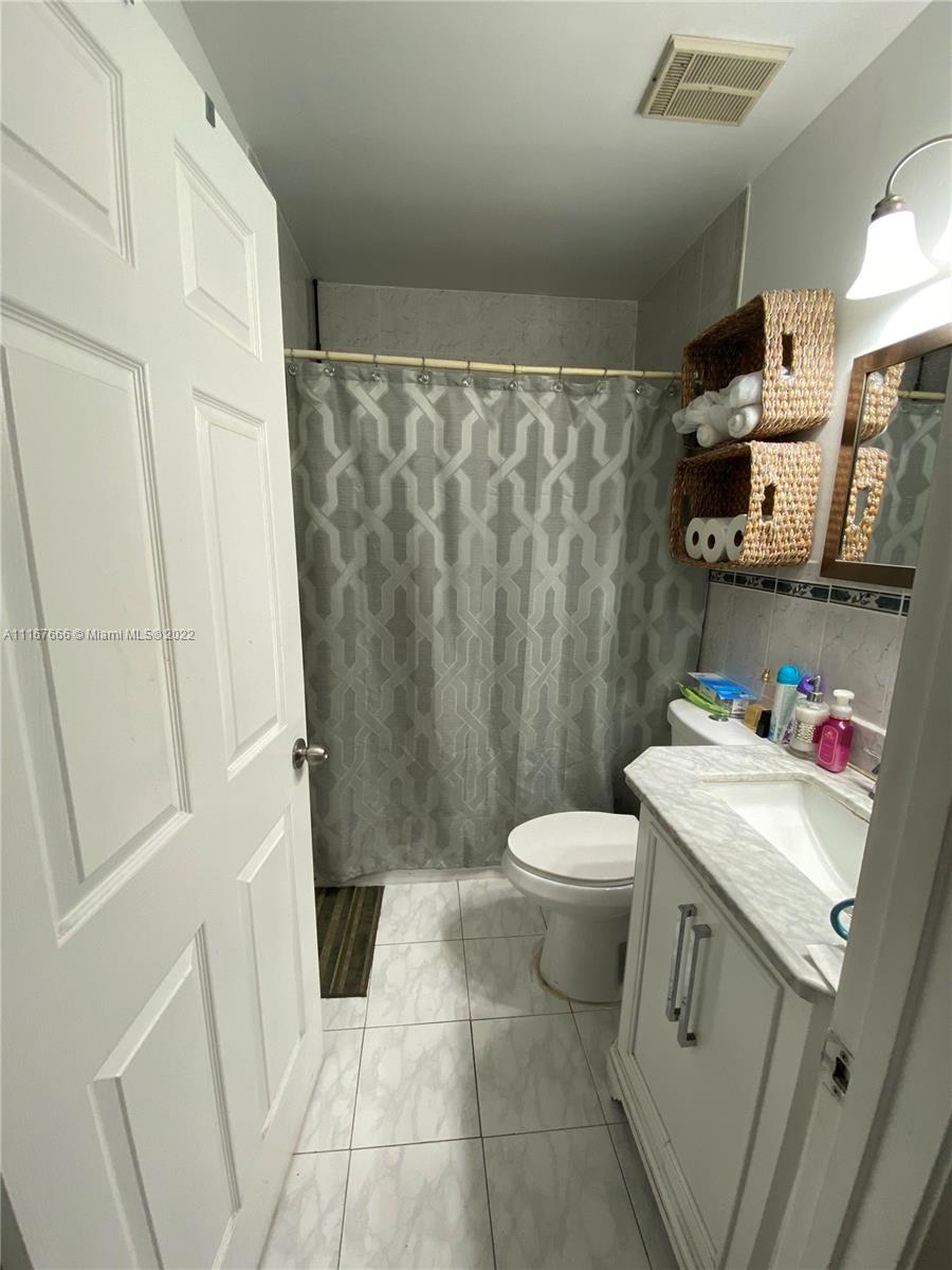 2879 West 75th Terrace Hialeah, FL 33018 - Photo 14 of 16 a bathroom with a sink a toilet and shower curtain