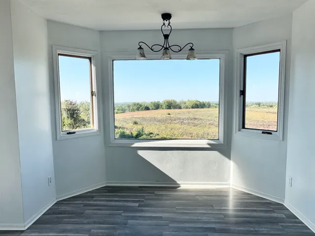a view of an empty room with wooden floor and window