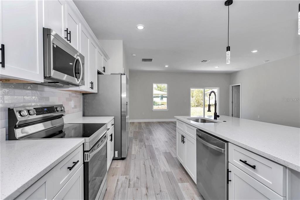 3875 Southwest 169th Ln Road Ocala, FL 34473 - Photo 19 of 46 a kitchen with stainless steel appliances granite countertop a sink a stove and a microwave