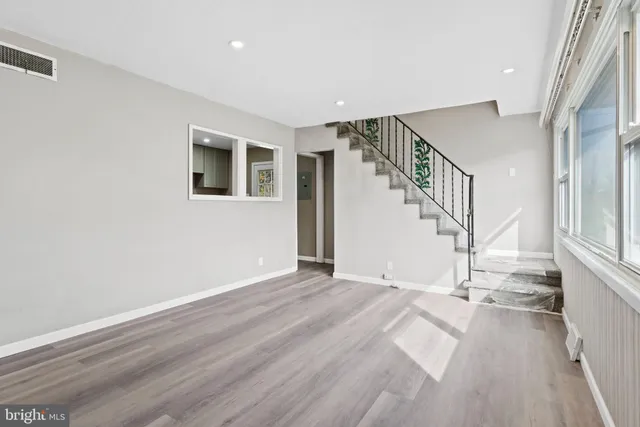 a view of an empty room with wooden floor and stairs