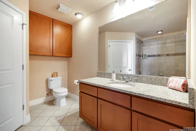 a bathroom with a granite countertop sink toilet and mirror