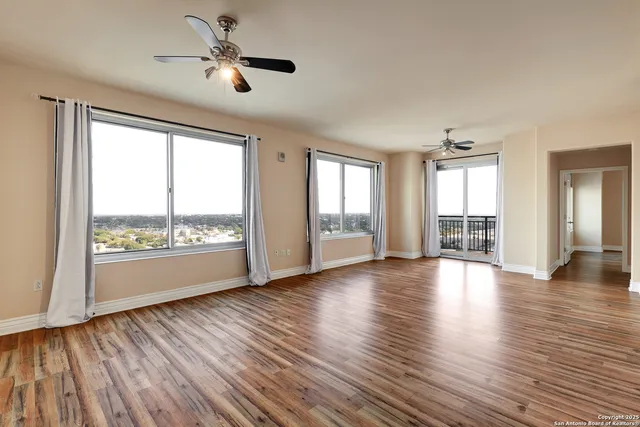 a view of an empty room with a window and wooden floor