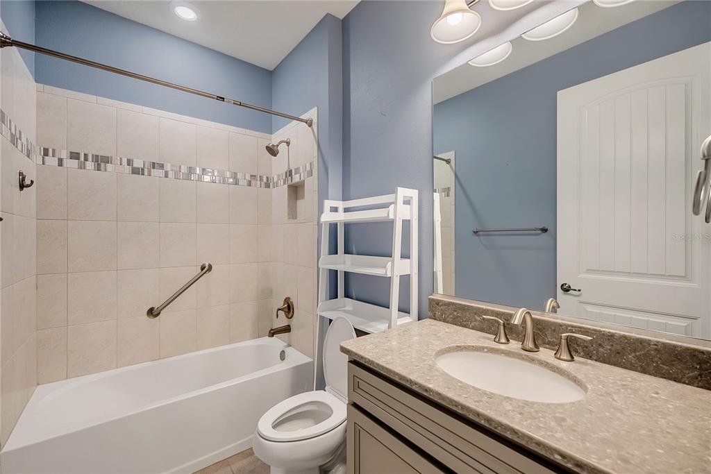 9550 Southwest 64th Lane Ocala, FL 34481 - Photo 29 of 58 a bathroom with a granite countertop sink a toilet a mirror a bathtub and shower