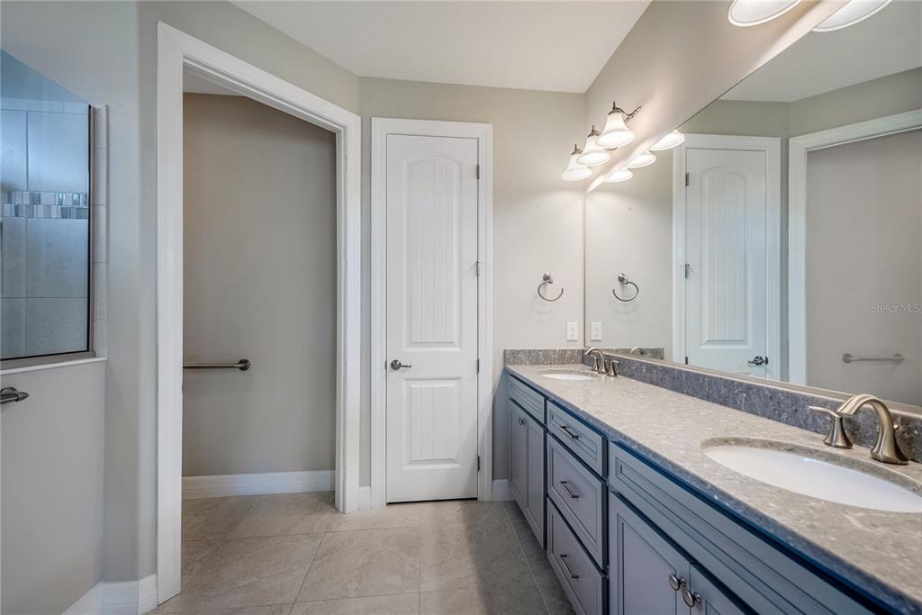 9550 Southwest 64th Lane Ocala, FL 34481 - Photo 36 of 58 a spacious bathroom with a granite countertop sink a mirror and a shower