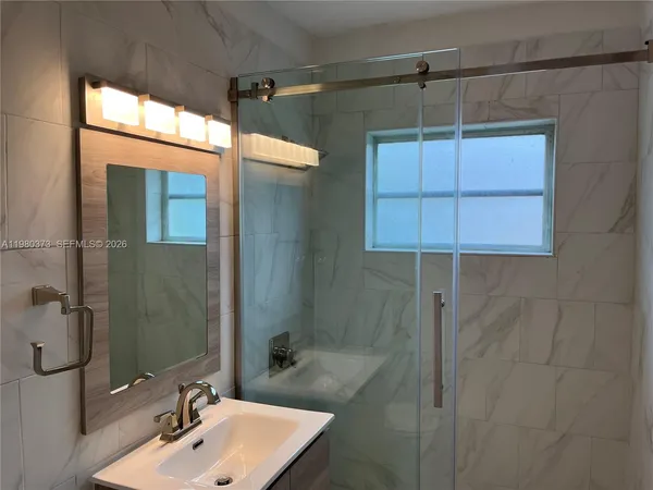 a bathroom with a sink shower and a mirror
