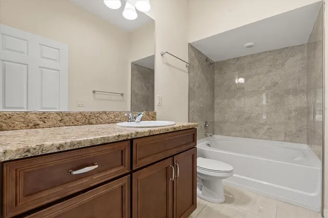 a bathroom with a granite countertop sink a toilet and bathtub