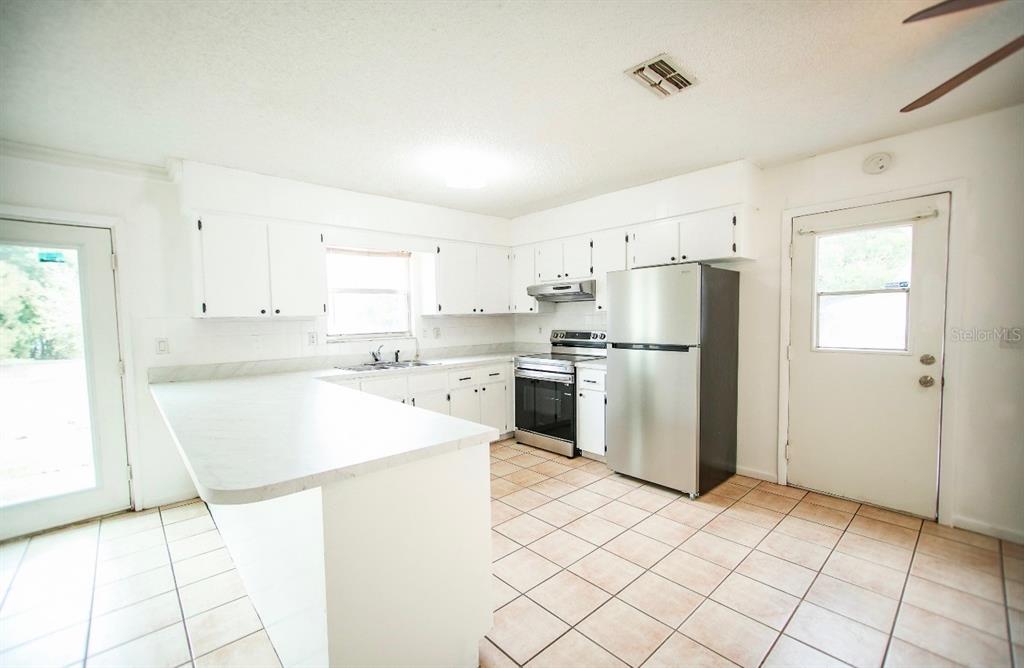 606 Water Road Ocala, FL 34472 - Photo 12 of 34 a kitchen with white cabinets a refrigerator and a stove top oven