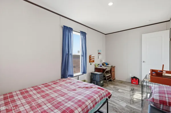 a bedroom with a bed a desk and chair with wooden floor